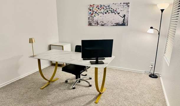 A white desk with a black monitor and a yellow chair in a room.