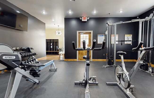 A gym with a variety of exercise equipment including treadmills, stationary bikes, and weight machines.