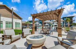 A patio with a fountain, chairs and a pergola.