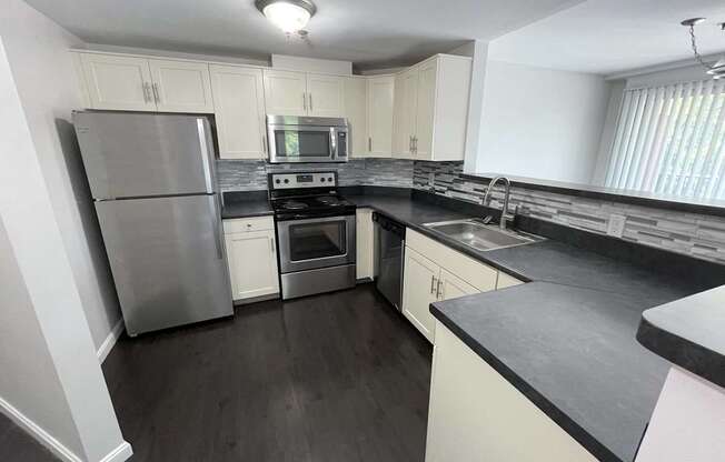 A kitchen with a stainless steel refrigerator, microwave, oven, and sink.