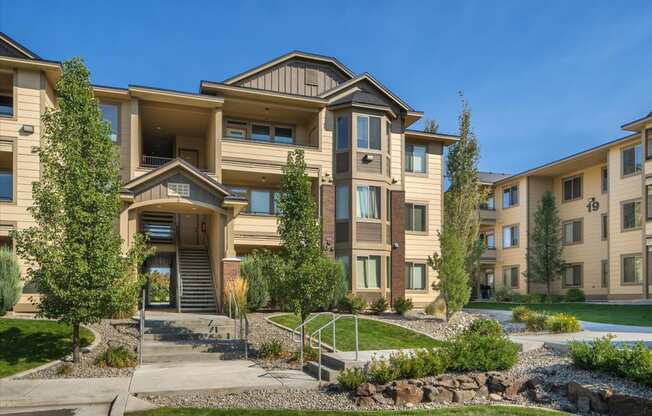 an apartment building with stairs and landscaping in front of it