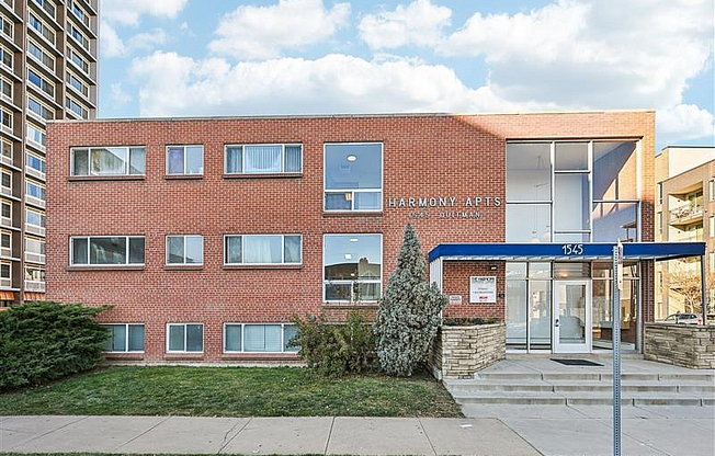 Inviting Harmony Apartments showcasing a charming brick exterior with modern windows and a welcoming entrance under a vibrant blue awning.