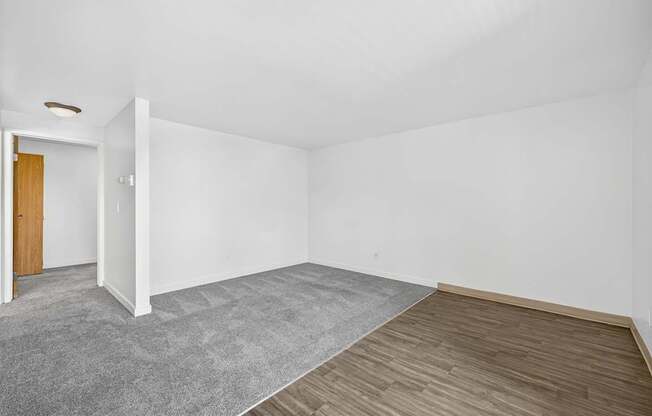 A room with a grey carpet and wooden flooring.