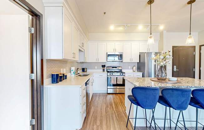 A kitchen with white appliances and blue chairs.