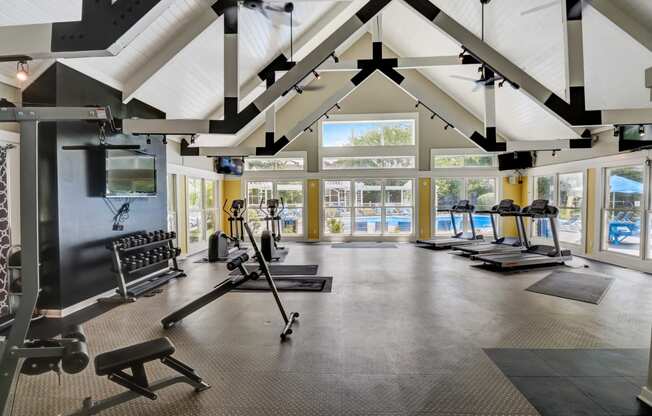 a large fitness room with exercise equipment and a view of the pool
