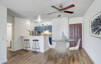 a dining area with a table and chairs and a kitchen in the background