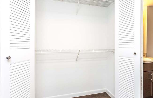 A white closet with a white door and a white shelf.