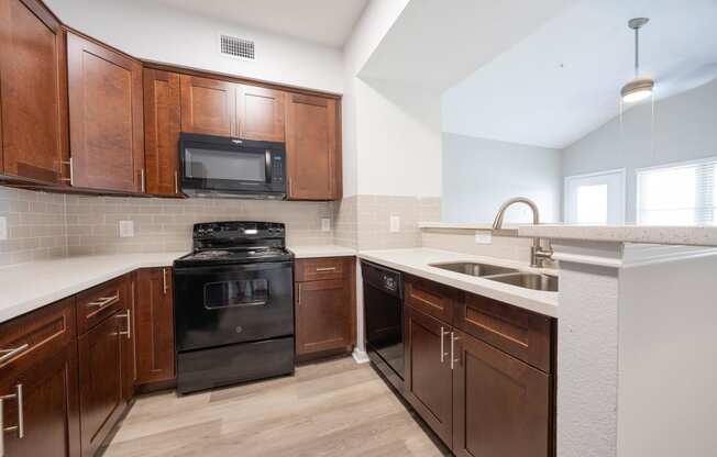 an empty kitchen with wooden cabinets and black appliances