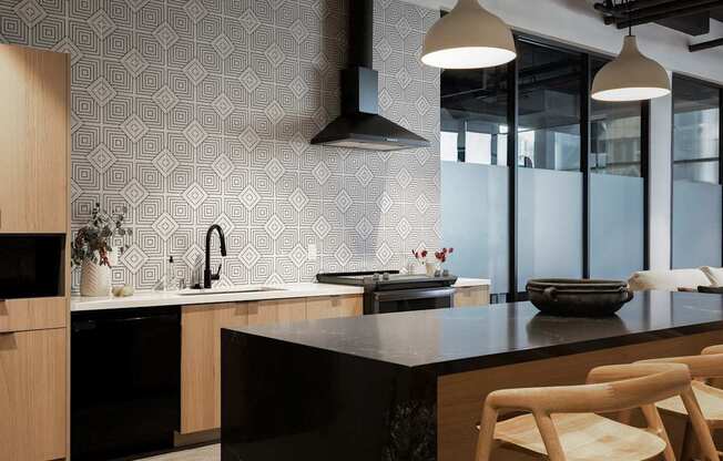 A modern kitchen with a black countertop and wooden chairs at Skylar At Sunset Apartments, Los Angeles 90027