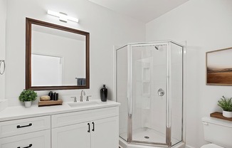 A white bathroom with a mirror, sink, and shower.