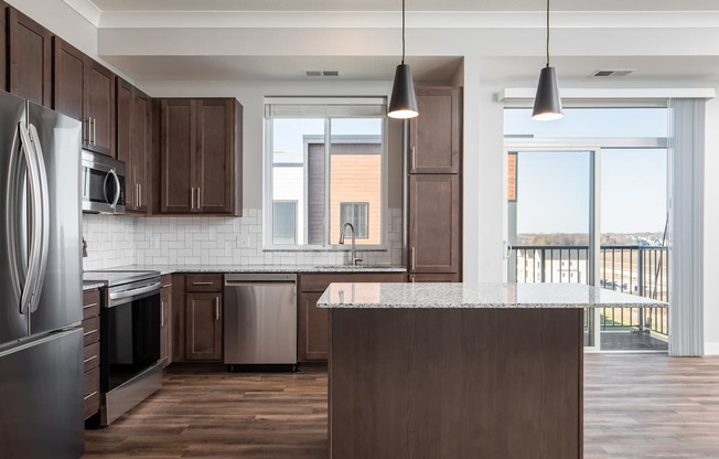 A kitchen with dark brown cabinets and a large island.