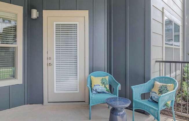 A balcony with a blue chair and a matching ottoman.