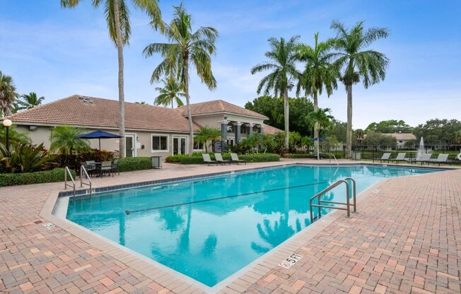 a swimming pool with palm trees in front of a house