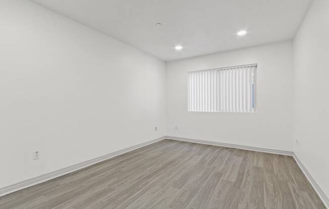 a room with white walls and wood floors and a window