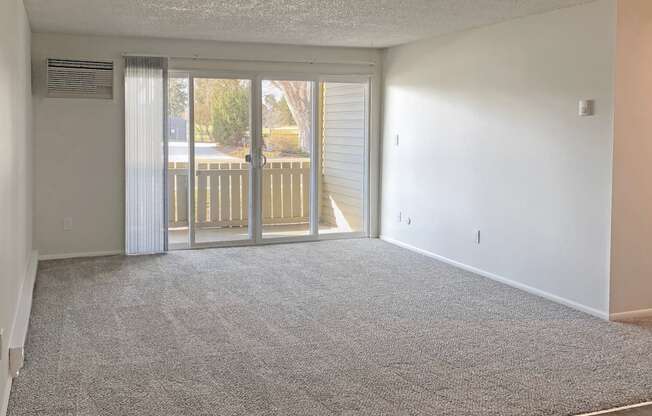 Spacious living room with gray carpet and large sliding glass doors to private patio in Boise, ID at Talavera.