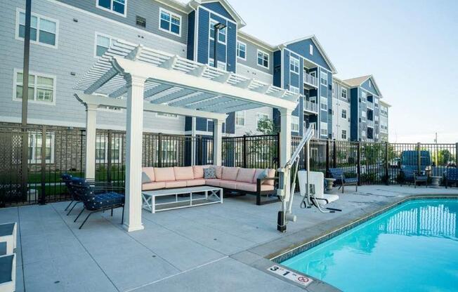 A pool area with a white pergola and a black fence.