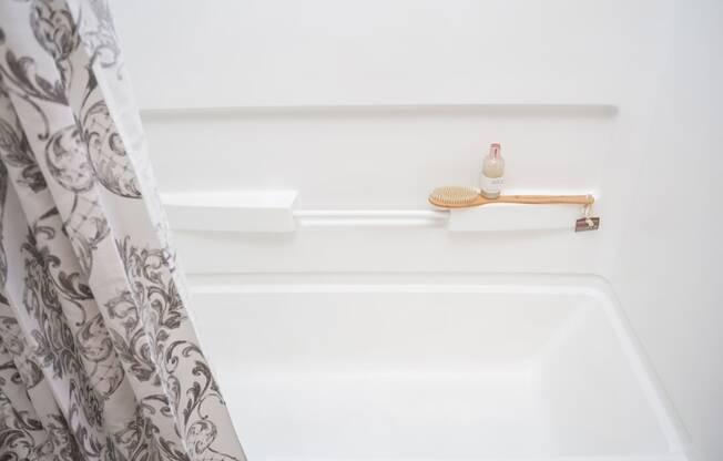 a white bathtub with a shower curtain and a soap dispenser on the shelf