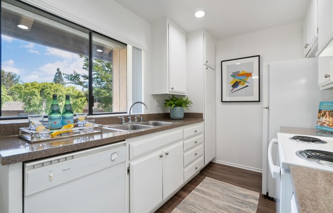 a kitchen with white cabinets and a sink and a window