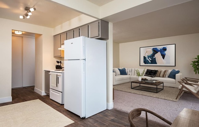 A white refrigerator stands in a living room with a couch and a coffee table.