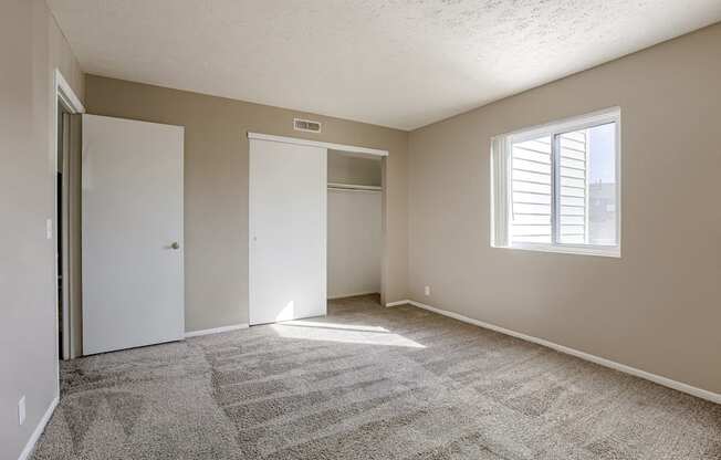A room with a carpeted floor and a window with blinds. Omaha, NE Evergreen Terrace Apartments