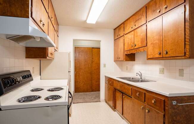 A kitchen with a white stove and wooden cabinets. Fargo, ND Islander Apartments