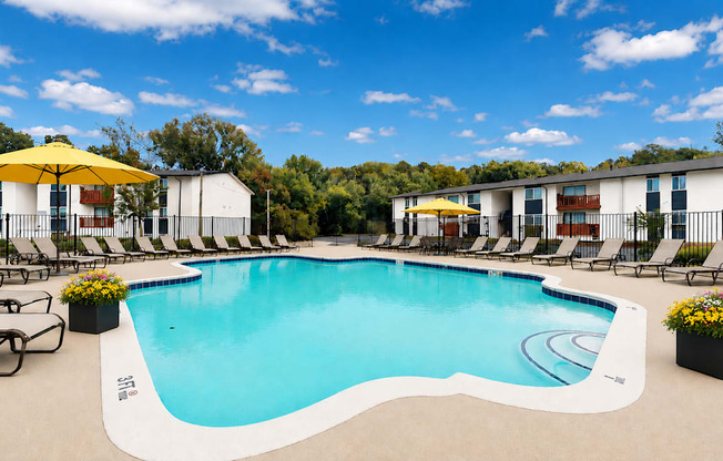 A large outdoor swimming pool surrounded by lounge chairs and umbrellas.