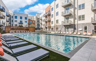 Sparkling resort style swimming pool with cushioned lounge chairs