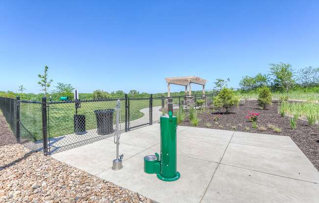 a fenced in area with a water fountain and trash cans