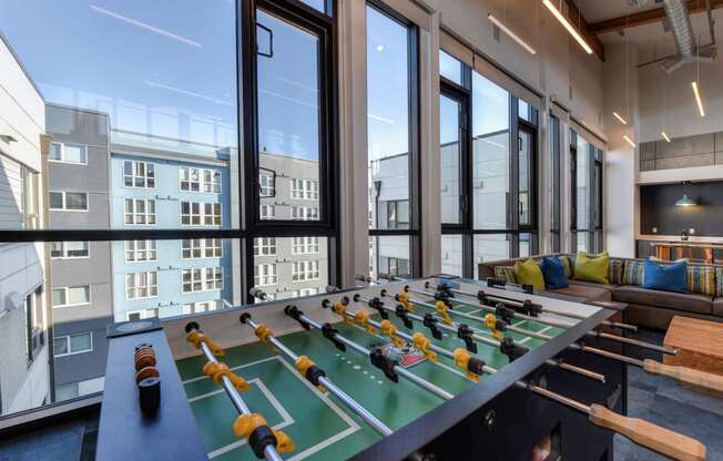 Community Clubhouse Foosball Table with View of Outside Apartment Exteriors through Large Window