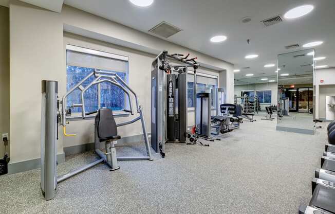 a gym with weights and cardio equipment in a building with windows