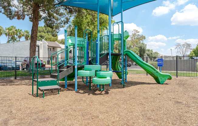 A playground with a green slide and a blue canopy.