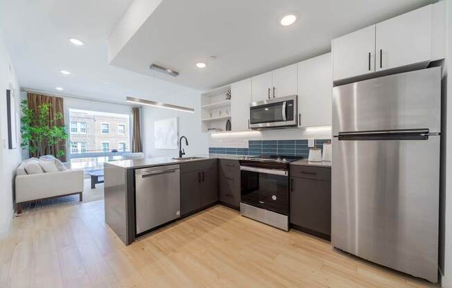 A modern kitchen with stainless steel appliances and wooden flooring.