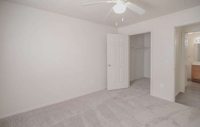 an empty bedroom with a ceiling fan and a closet