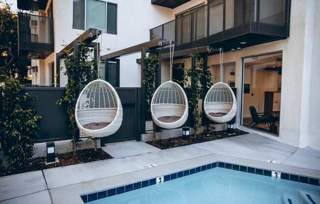 Pool with an outdoor hanging rattan egg chairs