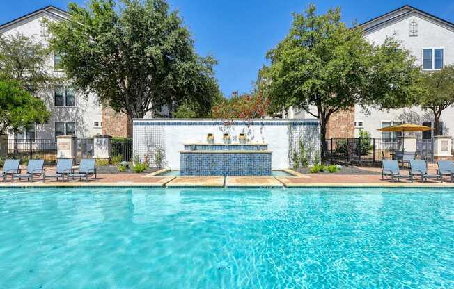 A swimming pool surrounded by trees and chairs.