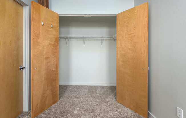 an empty closet with two wooden doors and a white wall