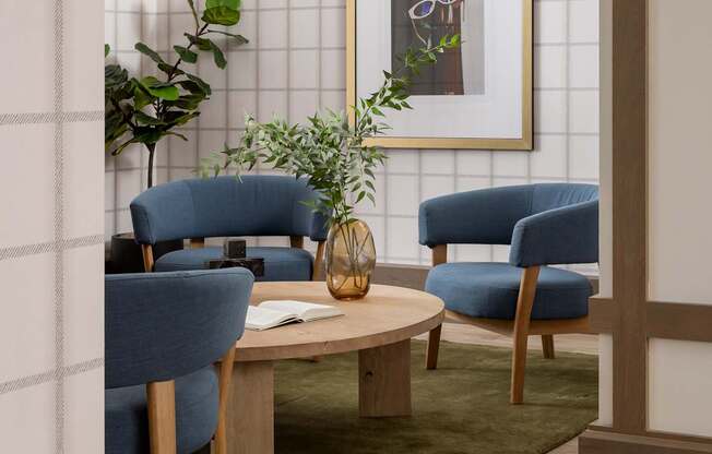 A living room with a blue chair, a wooden table, and a framed picture on the wall.