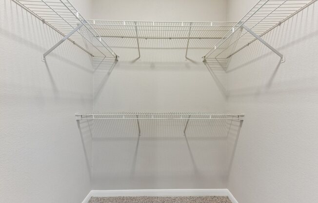 Empty wire shelves in a white refrigerator.