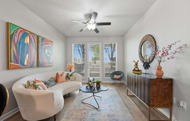 A living room with a white couch, a coffee table, and a ceiling fan.