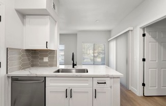 A modern kitchen with white cabinets and a marble countertop.