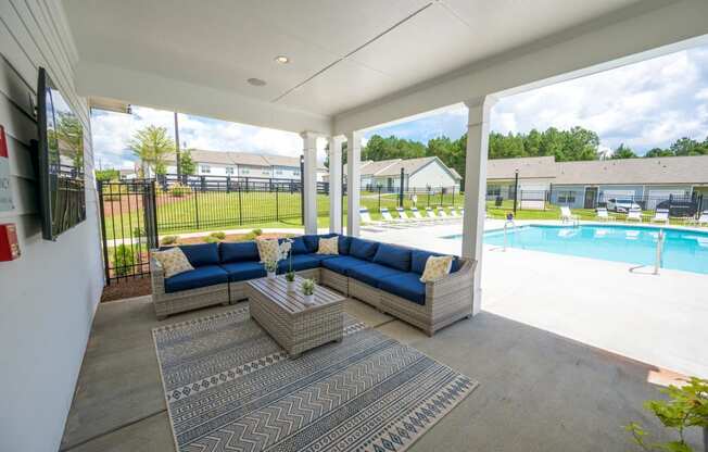 a covered patio with couches and a table next to a pool