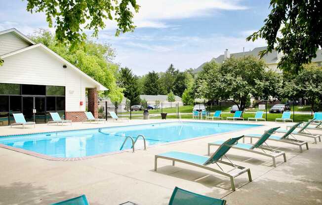 A pool with sun loungers and a building in the background.
