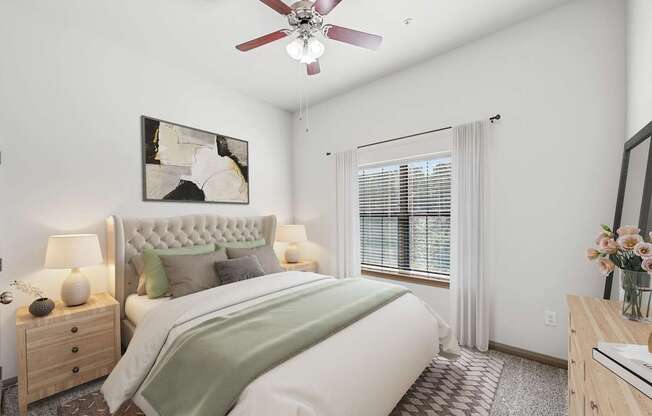 A bedroom with a large bed, a ceiling fan, and a painting on the wall.