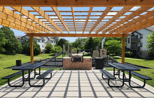 A wooden pergola over a picnic table in a park.