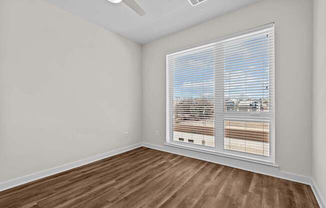 A room with a window covered by white blinds.