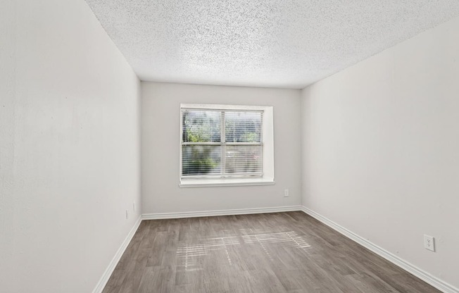 A room with a window and wooden flooring.
