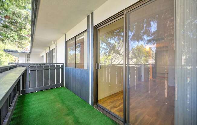 A balcony with glass doors and a green carpet.