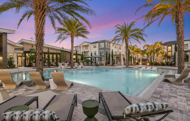 a swimming pool with chaise lounge chairs and palm trees