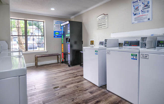 a laundry room with four washes and dryers in it and a window