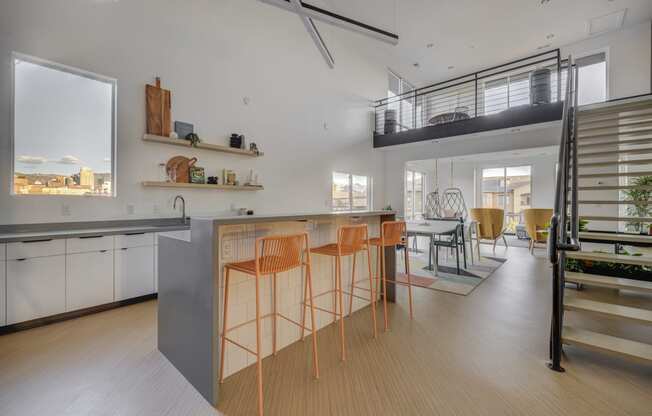 clubroom kitchen with a large island with stools and  a staircase